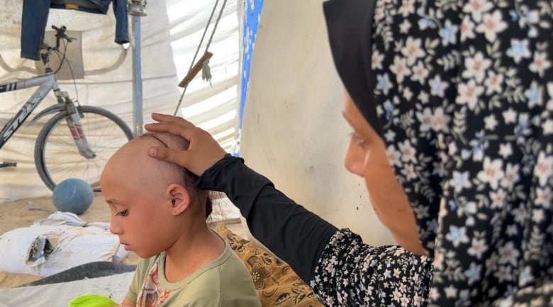 A mother puts her palm on her daughter's head.