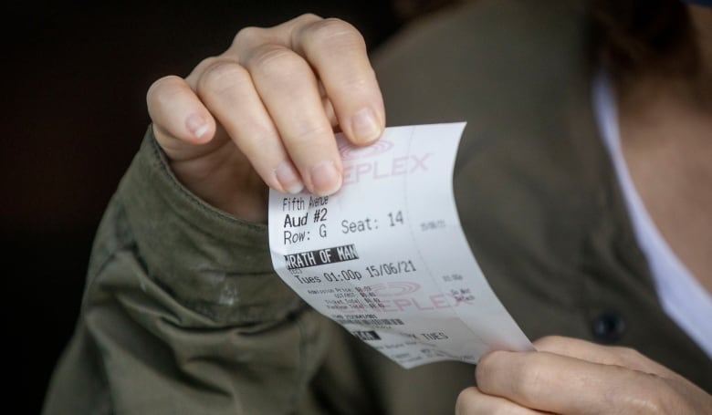 Close-up of hands holding a movie theatre ticket. 