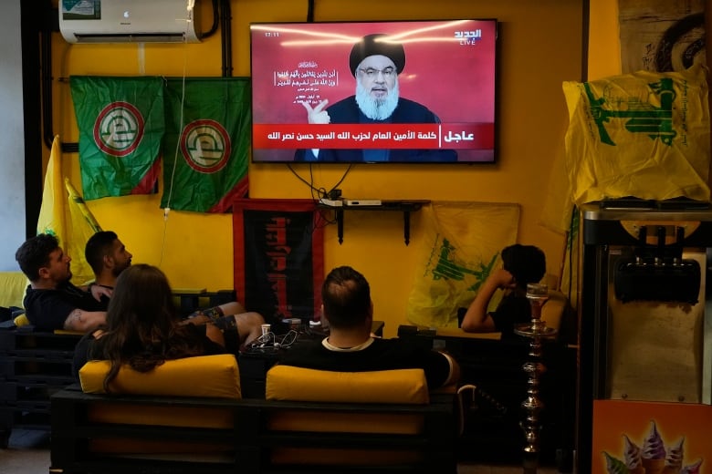 People watch the speech of Hezbollah leader Hassan Nasrallah as they sit in a cafe in the southern suburbs of Beirut, Thursday, Sept. 19, 2024. 