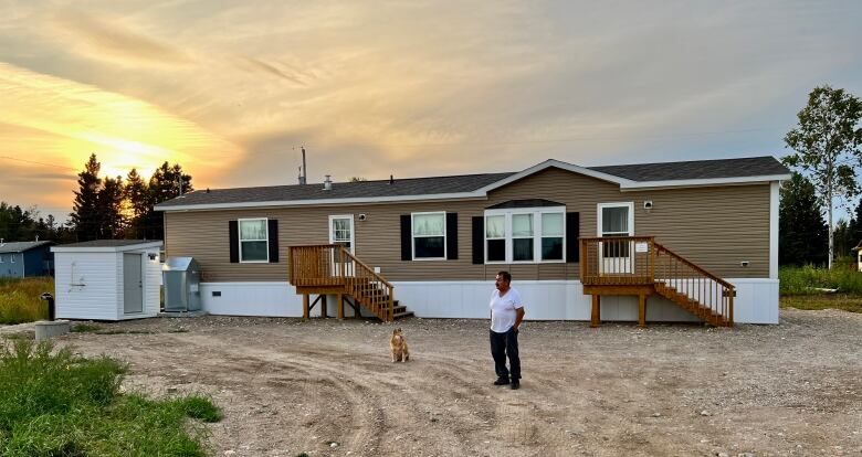 A man and a dog stand outside a home.