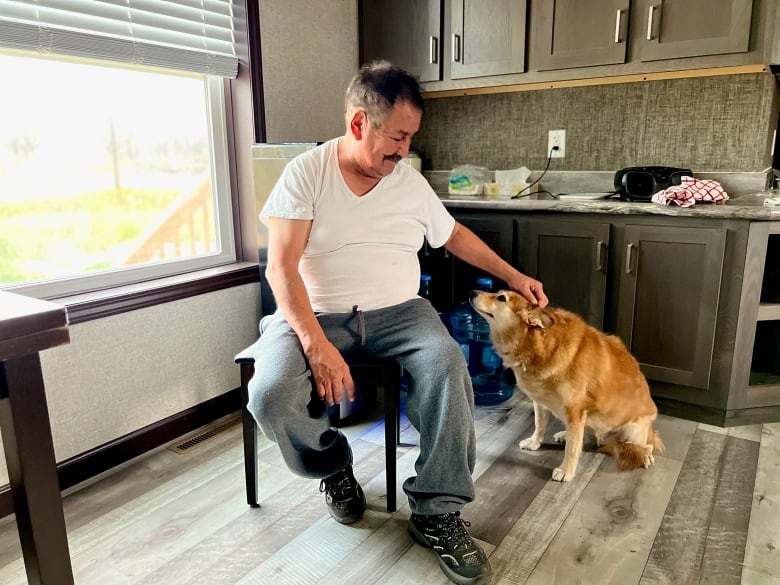 A man and dog sit inside the dining room of a home.