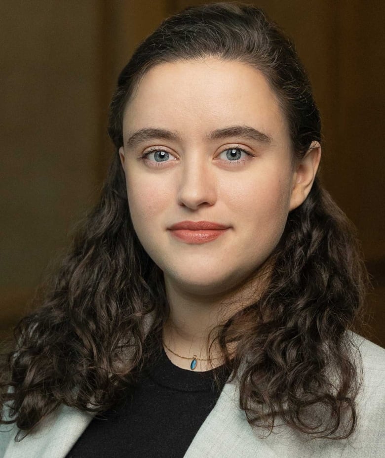 A portrait of a smiling young woman with long, curly, dark hair.