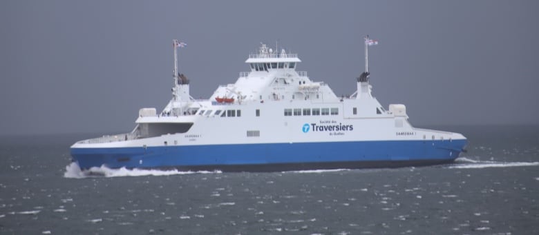 A white and blue ship goes through choppy seas.