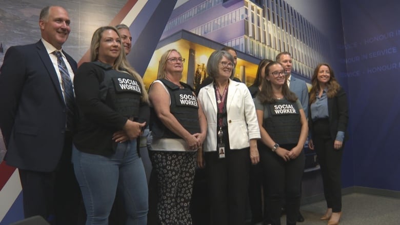 group of people stand in front of a Windsor police wall banner