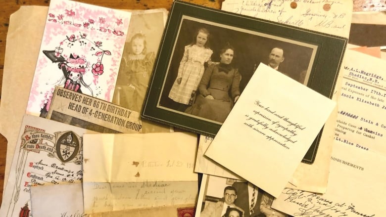 Photos, letters and newspaper clippings scattered on a table.