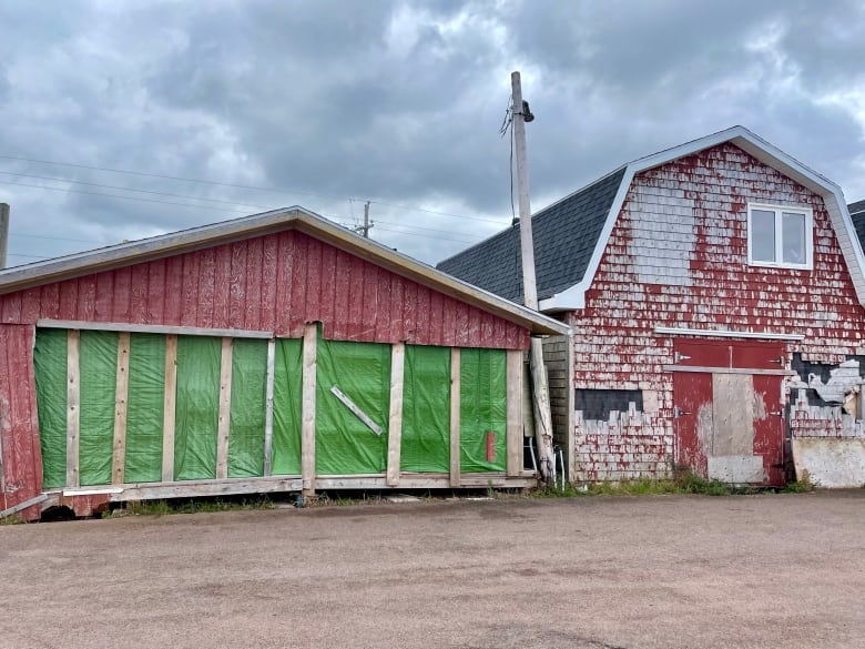 Damaged red buildings on a fishing wharf.