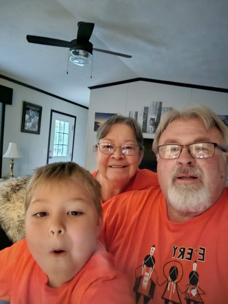 Three people posing for photo with 'Every child matters' orange shirts.