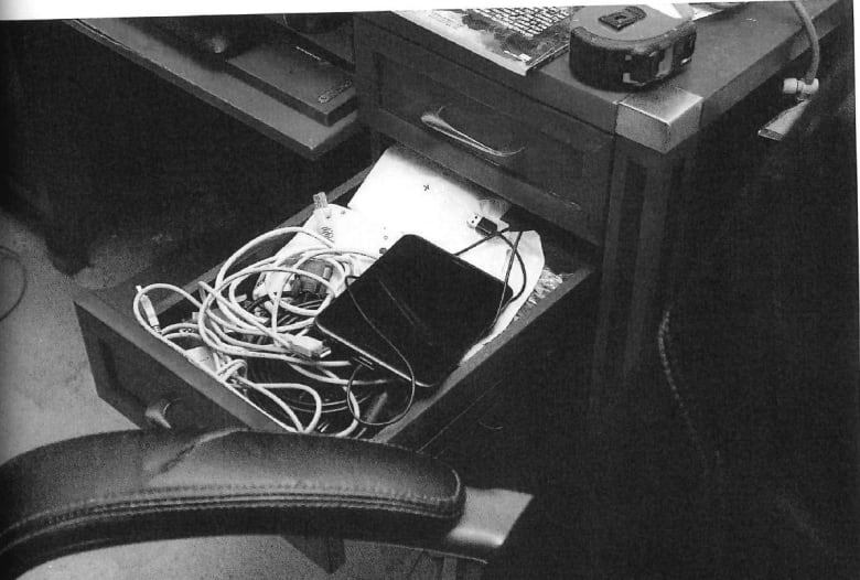 A desk draw is open and shows a mess of wires and an a device sitting on top.