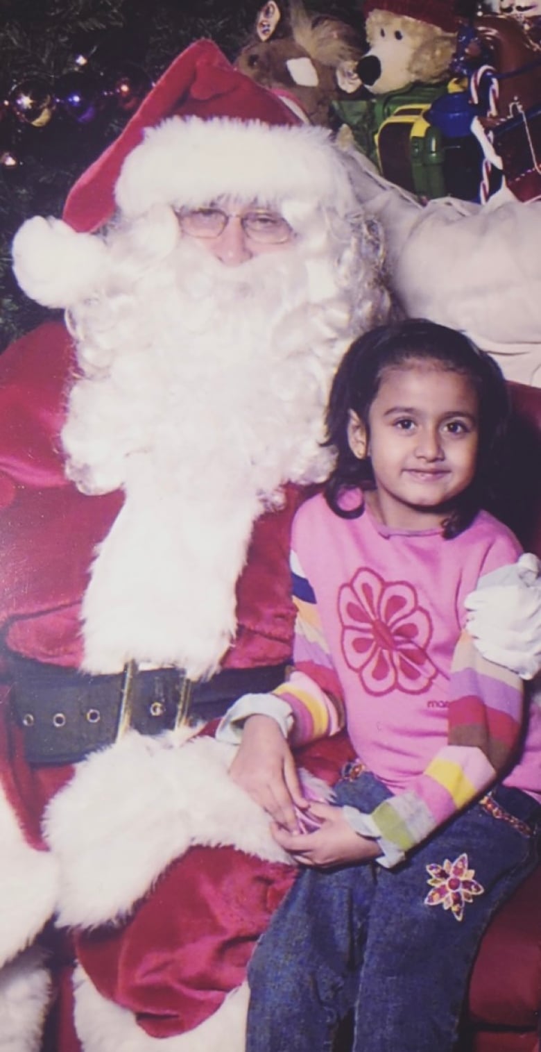 A girl sits on Santa's lap in an old photo.