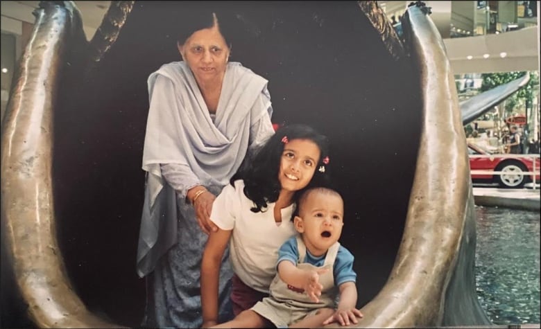 A baby, girl and woman inside a water sculpture. 