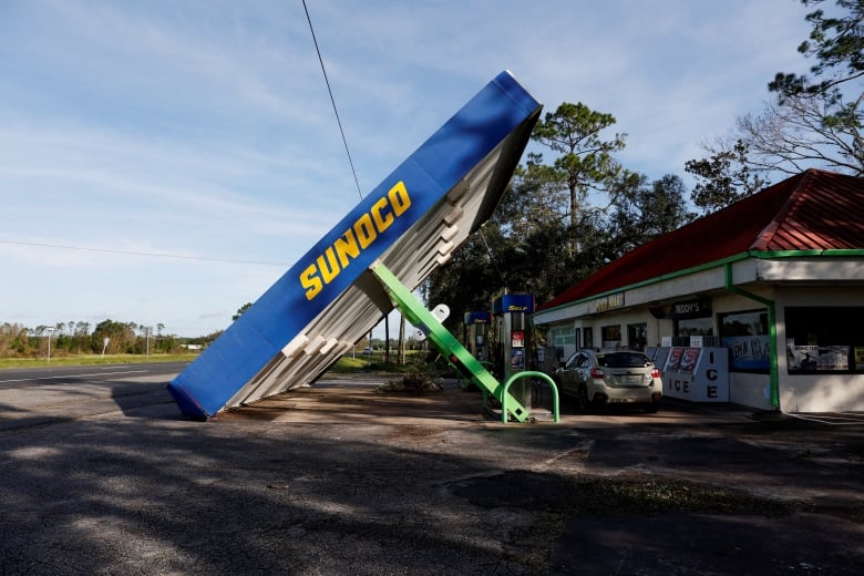 The covering above gas pumps is shown crashed and fallen to the ground at an angle at a station.