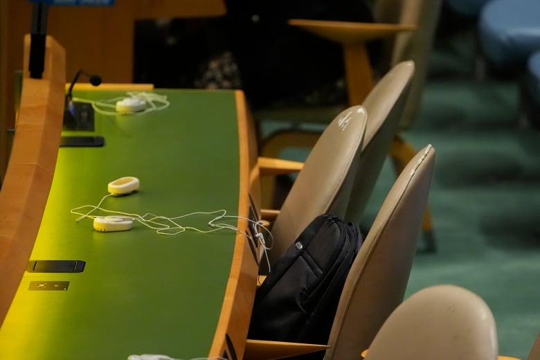 Empty chairs and one backpack are shown at a long table.