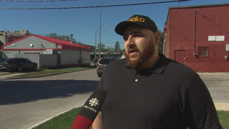 A man stands and speaks to the camera. 