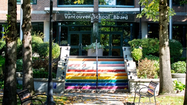 A building marked 'Vancouver School Board', with rainbow-coloured steps leading up to it.