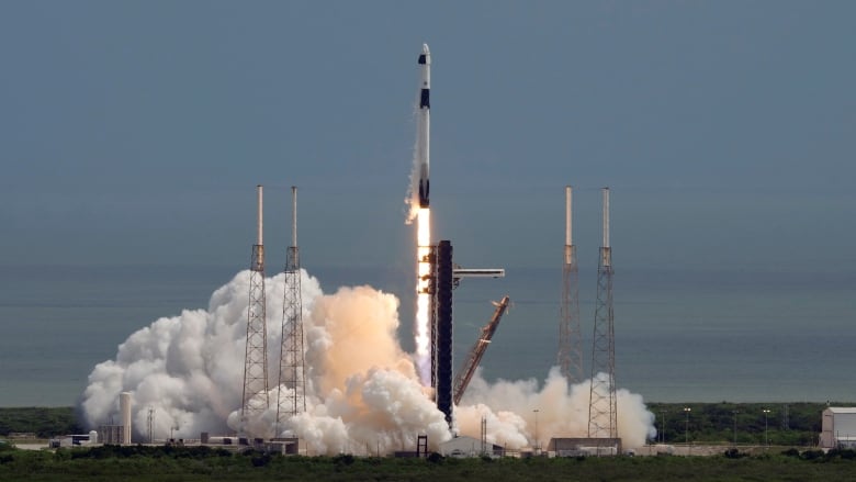 A spacecraft blasts off from a launch pad.