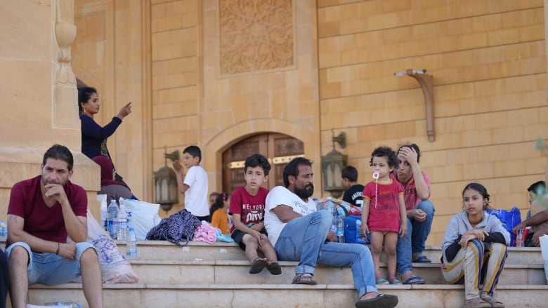 People displaced by Israeli airstrikes on Lebanon rest on the steps of the Mohammad Al Amin Mosque in Beirut.