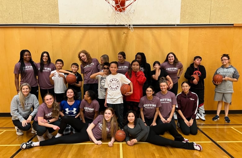 young women athletes pose with pre-teen kids and basketballs in a gym