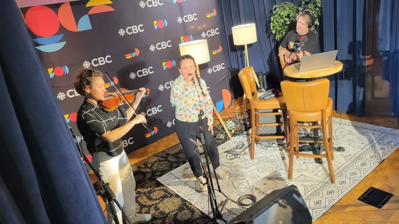 Mainstreet host Jeff Douglas watches as violinist Gina Burgess and throat singer Kathleen Merritt perform inside Church Brewing Co. in Wolfville, N.S.