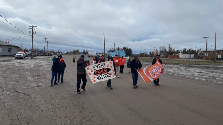 People walking wearing orange shirts and carrying handpainted signs saying every child matters