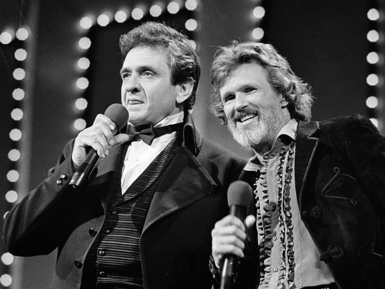 Two singers holding microphones perform in this black and white photo.