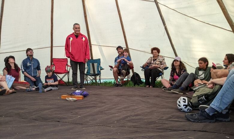 Man speaks to group in teepee