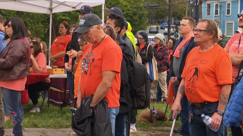 A crowd of people bow their heads in prayer.