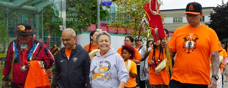 Three people smiling as they walk at the front of the line. 