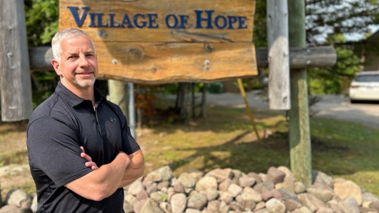 Man standing in front of wooden sign