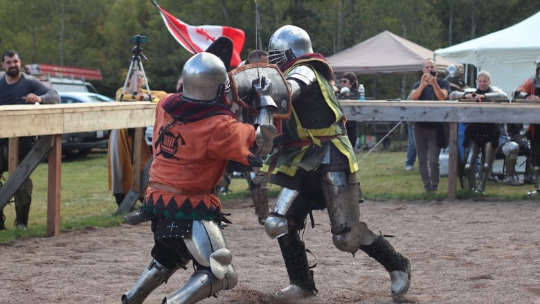 one person in medieval titanium armour lunges at another fully armoured individual with a sword