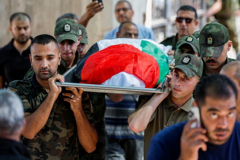 People carry a body wrapped in the Palestinian flag.