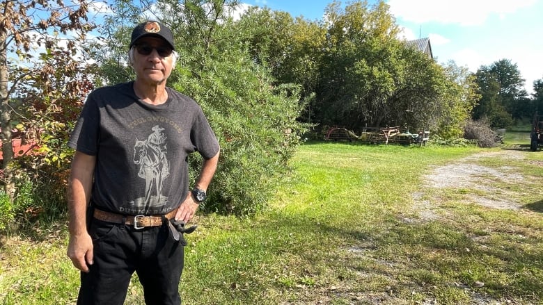 A man stands near his farmland. 