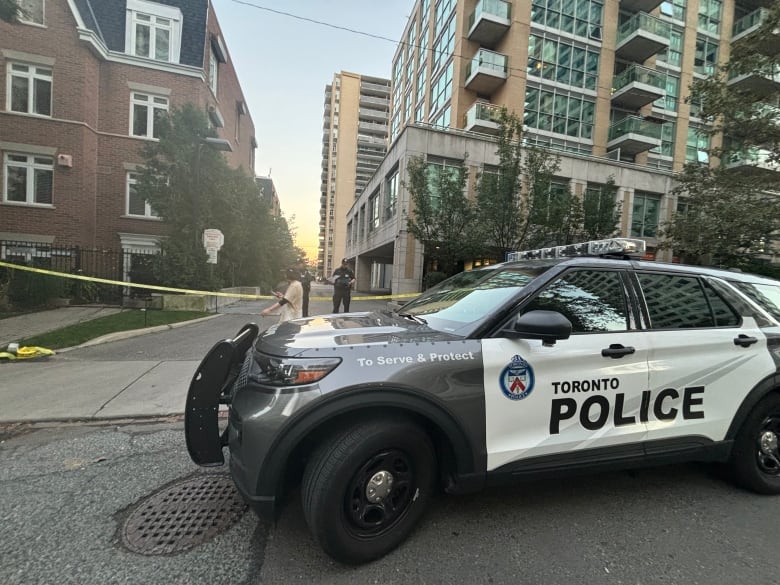 A Toronto police cruiser sits in front of police tape.