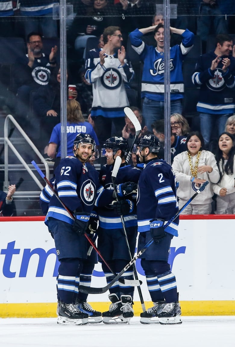 A group of men on hockey gear hug.