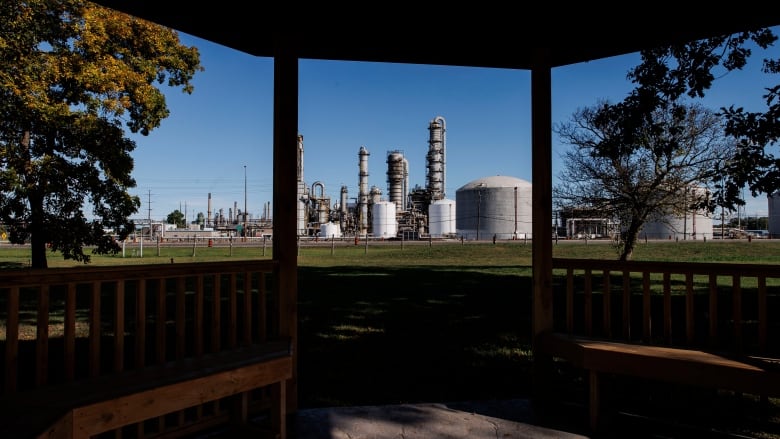 A chemical plant is framed from a gazebo on a reserve, during a sunny day.