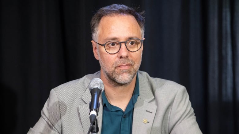 A man sits before a microphone. 