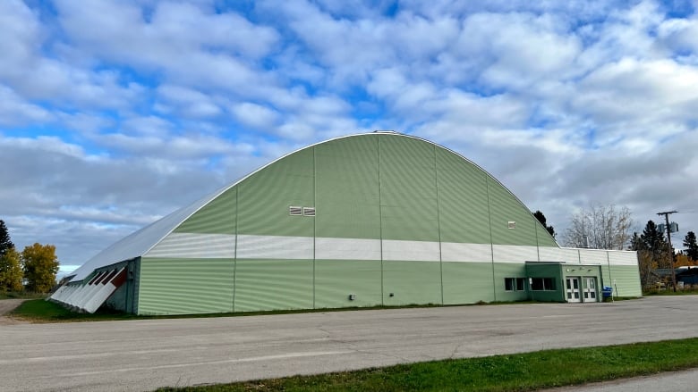 A green arena building, seen from the outside.