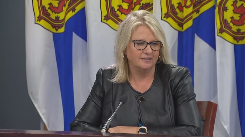 Woman in leather blazer sits near four flags