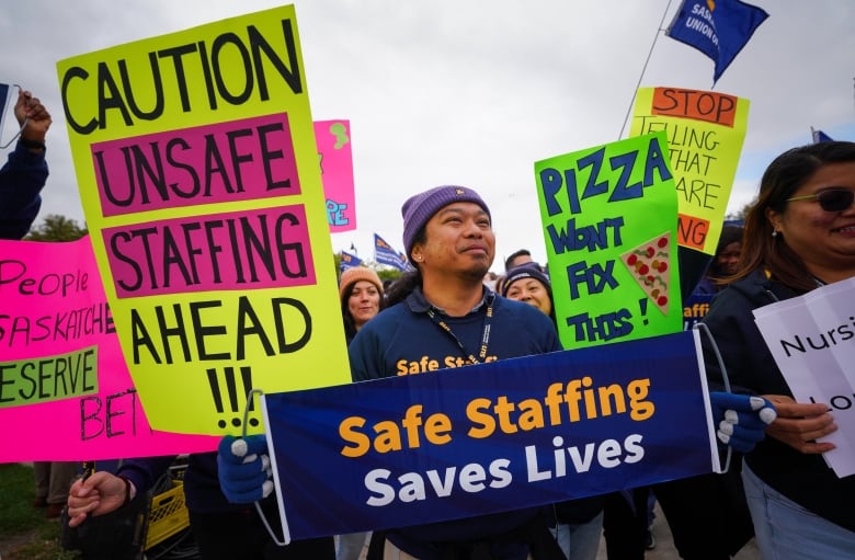 Several people hold signs calling for better health-care staffing.