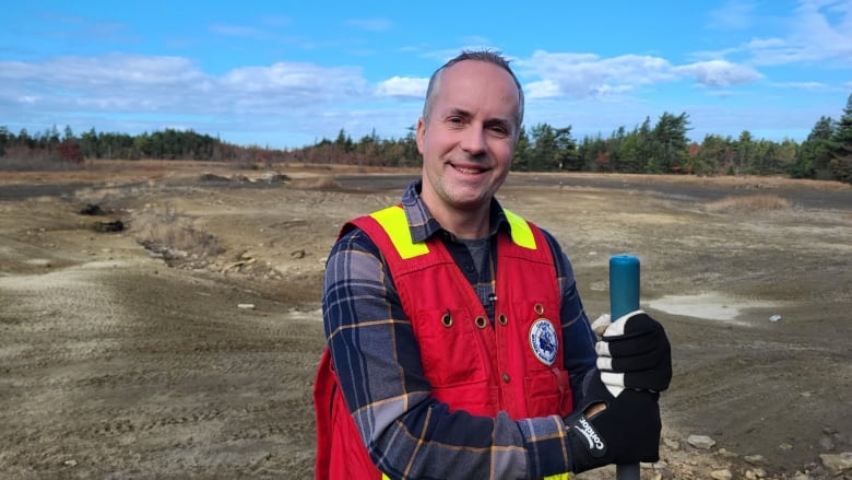 Man posing with a shovel in front of a dusty area. 