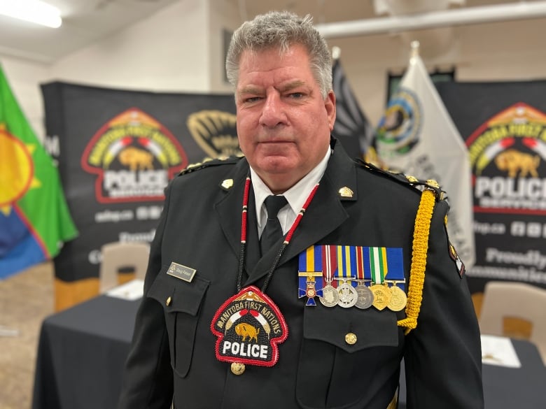 A man in a police uniform stands in front of a table and a podium. 