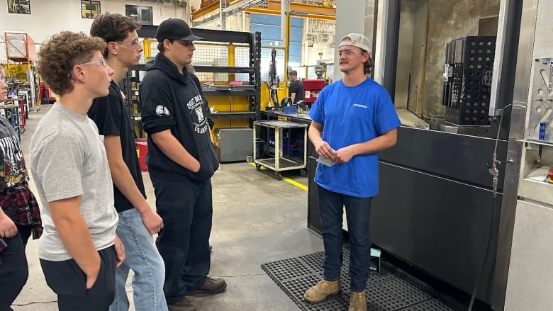 A man in an industrial space speaks to a group of people.