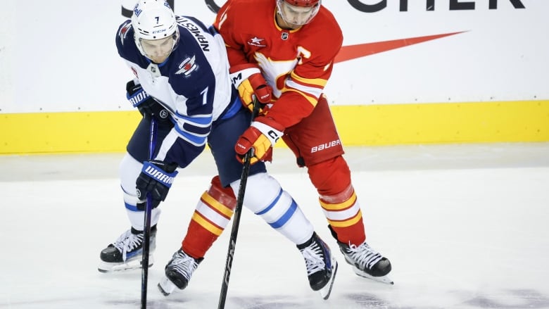 Two hockey players looking at a puck