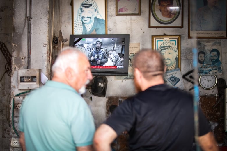 People watch a wall-mounted television.