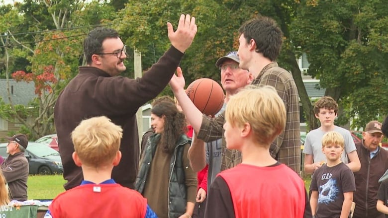 Two men performing a ceremonial tip-off with a basketball.