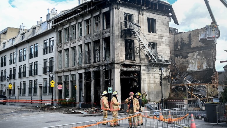 Firefighters stand next to a building in Old Montreal on Saturday, Oct., 5, 2024. 