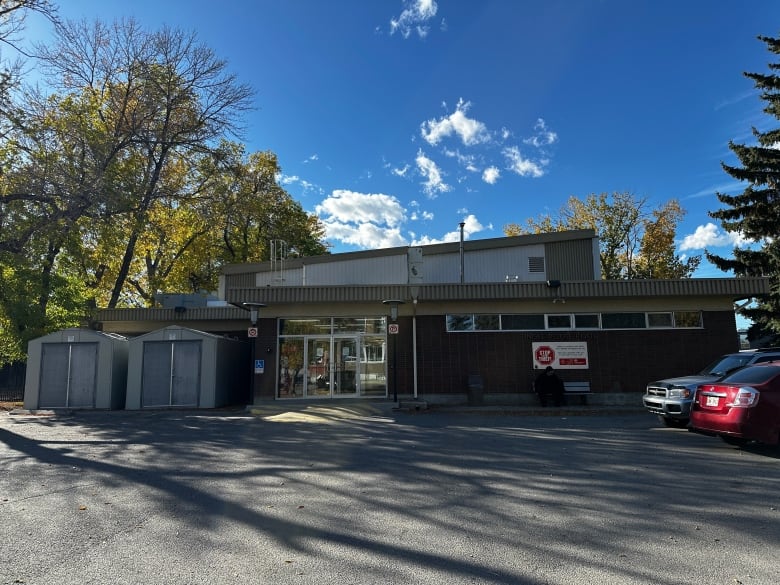 A single story building with two cars parked in front of it.