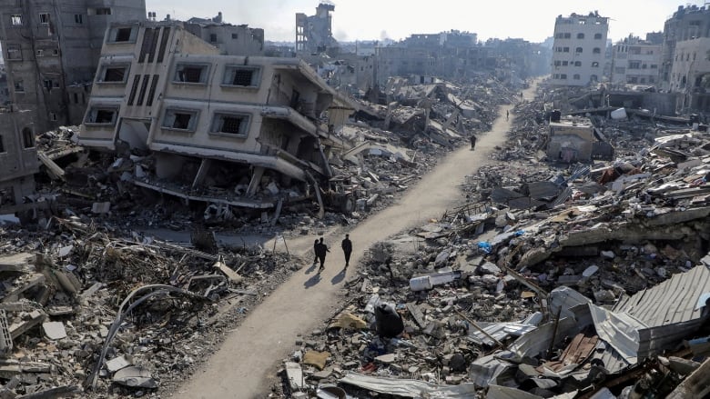 Palestinians walk past destroyed houses, amid the ongoing conflict between Israel and Hamas, in Jabalia refugee camp, in the northern Gaza Strip February 22, 2024.