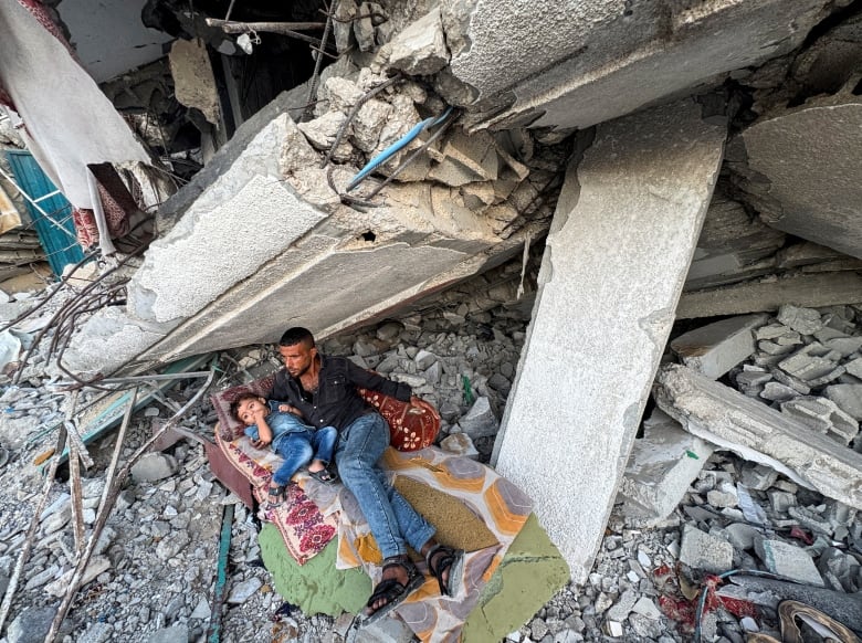 Palestinians rest under the rubble of a house destroyed in Israeli strikes, amid the Israel-Hamas conflict, in Khan Younis in the the southern Gaza Strip, September 26, 2024