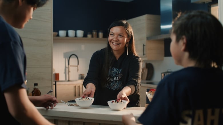 A woman hands out bowls of oatmeal to two youth.