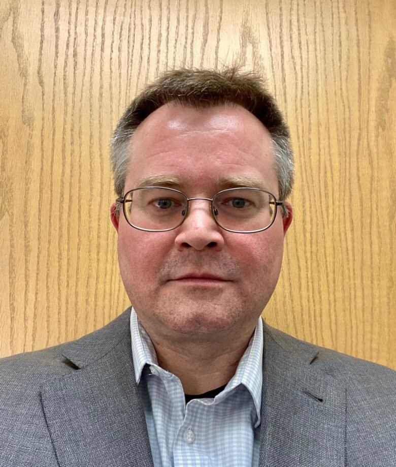 Headshot of a man wearing a grey jacket.